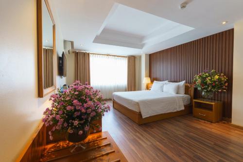 una habitación de hotel con una cama y flores en una habitación en Roseland Corp Hotel, en Ho Chi Minh