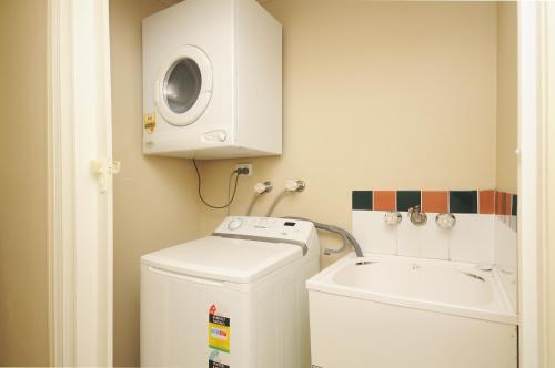 a bathroom with a washing machine and a sink at Nautilus Holiday Apartments in Port Douglas