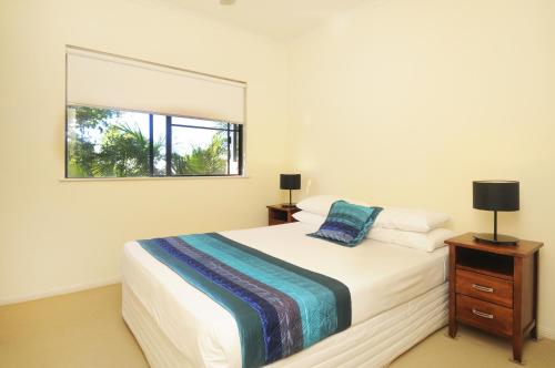 a bedroom with a large bed and a window at Nautilus Holiday Apartments in Port Douglas