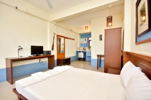 a bedroom with a large white bed and a desk at Agos Boracay Rooms + Beds in Boracay