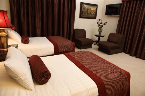 a hotel room with two beds and a chair at Hisham Hotel in Amman
