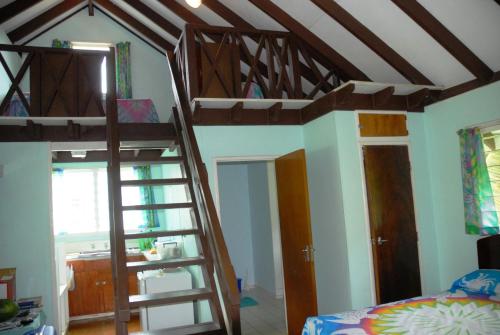 a bedroom with two bunk beds and a ladder at Ginas Garden Lodges, Aitutaki - 4 self contained lodges in a beautiful garden in Arutanga