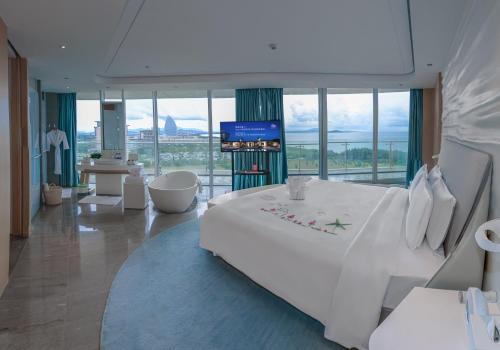 三亜市にあるThe Mangrovetree Sanya Resortの白い大型ベッドとテレビが備わるホテルルームです。