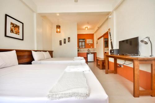 a hotel room with two beds and a television at Agos Boracay Rooms + Beds in Boracay