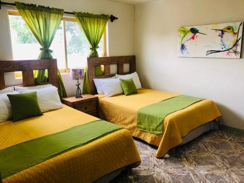 - une chambre avec 2 lits avec des draps verts et jaunes dans l'établissement Finca Ybarra, casa de campo, à Chapala
