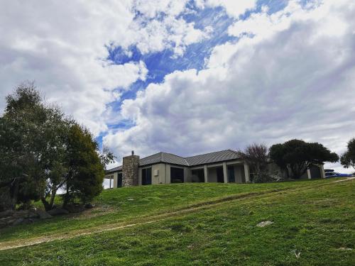 a house on top of a grassy hill with a house at Snowy Mountains Retreat in Moonbah