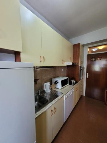 cocina con armarios blancos, fregadero y microondas en Soleil Central Apartments, en Skopje
