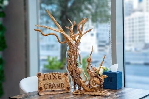 a vase with a tree and a sign on a table at Luxe Grand Hotel Apartments in Sharjah