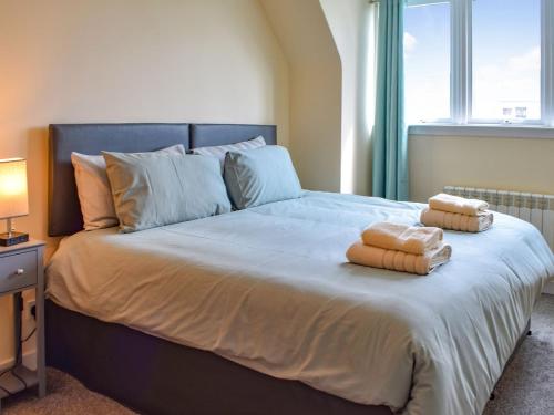 a bedroom with a large bed with two towels on it at Burnside Cottage in Bruichladdich