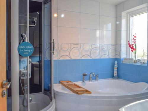 a bathroom with a tub and a sink and a shower at Burnside Cottage in Bruichladdich