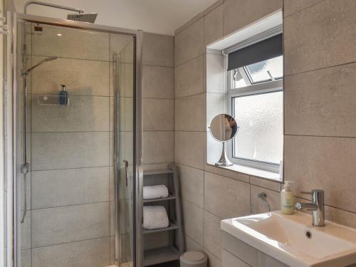 W łazience znajduje się prysznic, umywalka i lustro. w obiekcie Old Road Cottage w mieście Conwy