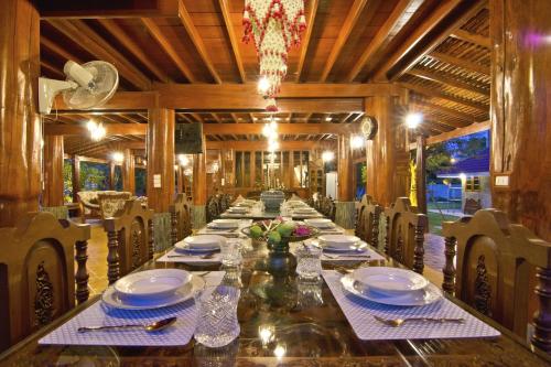 Ban Huai Yai的住宿－標布阿通度假村，长长的用餐室配有长桌