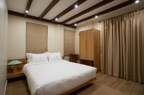 a bedroom with a large white bed and a window at Karuna Hotel Patan Kathmandu in Pātan