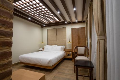 een hotelkamer met een bed en een stoel bij Karuna Hotel Patan Kathmandu in Pātan
