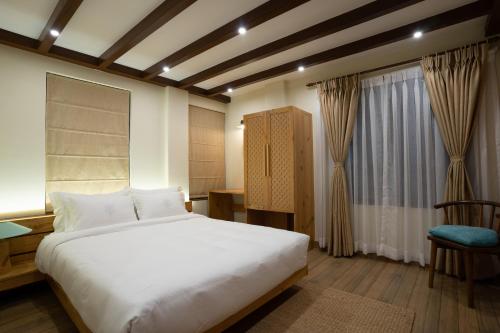帕坦Karuna Hotel Patan Kathmandu的一间卧室，里面有一张床、一把椅子和一扇窗户