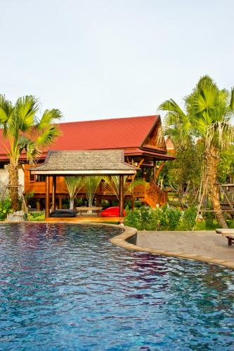 a house with a swimming pool in front of a building at Bueng Bua Thong Resort in Ban Huai Yai