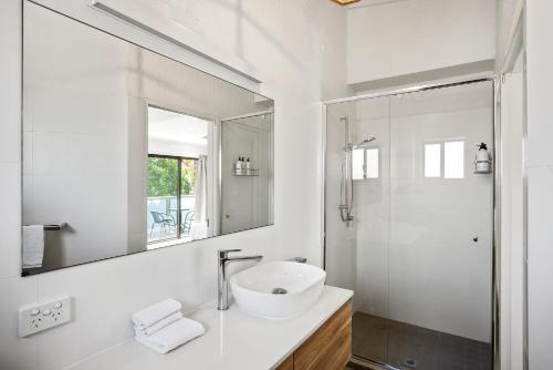 a white bathroom with a sink and a shower at The Terraces Main Beach in Byron Bay