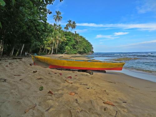 a yellow and red boat sitting on the beach at La Kukula Lodge in Puerto Viejo