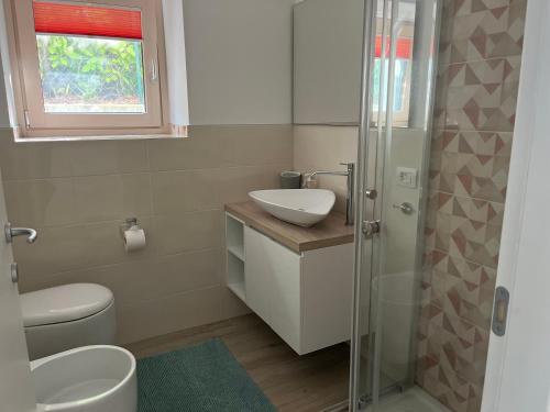 een badkamer met een wastafel, een toilet en een douche bij lido 3 con piscina in Colico