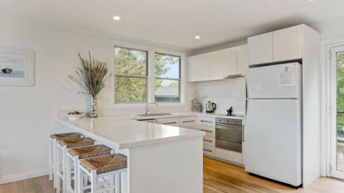a kitchen with white cabinets and a white refrigerator at 55 The Boulevarde Hawks Nest in Hawks Nest
