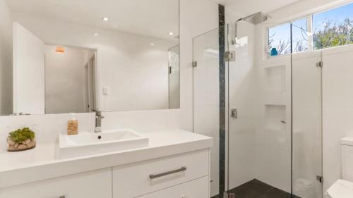 a white bathroom with a sink and a shower at 55 The Boulevarde Hawks Nest in Hawks Nest