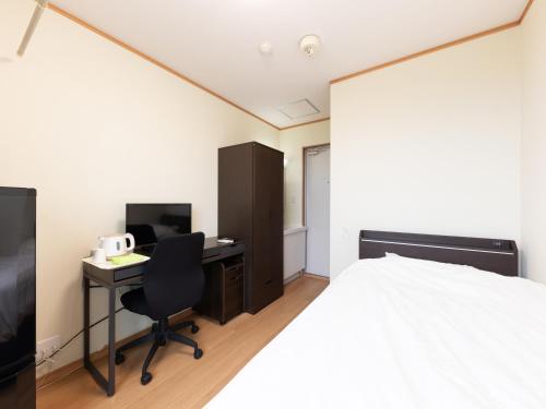 a bedroom with a bed and a desk with a computer at Tabist Hotel Takagiya Iwaki in Hisanohama