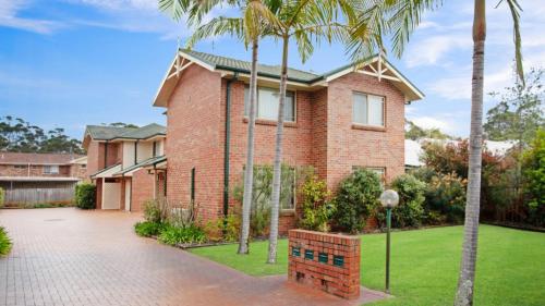 a brick house with palm trees in the yard at 1 - 4 Bowral St Hawks Nest in Hawks Nest