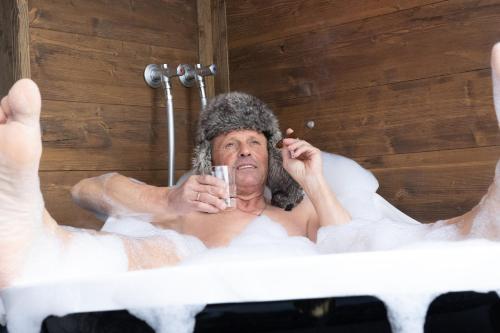 a man sitting in a bath tub holding a toothbrush at Luxury Apart Sailers including Premium Summercard in Sankt Anton am Arlberg