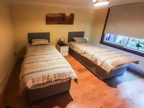 two twin beds in a room with a window at Hilbre in Strachur