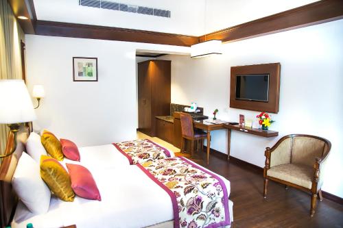 a hotel room with a bed and a desk and a television at Shervani Hilltop Resort in Nainital