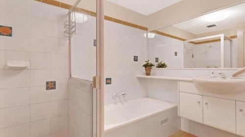 a white bathroom with a tub and a sink at 1 Aquarius 9 Beach Rd Hawks Nest in Hawks Nest