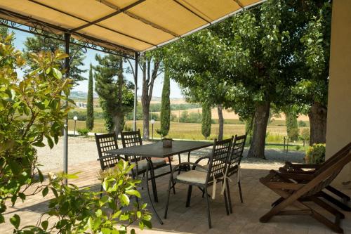 a patio with a table and chairs and trees at Agriturismo San Marcello in Castiglione dʼOrcia