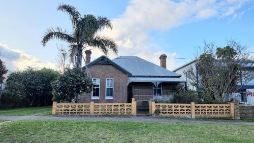 a house with a wooden fence and a palm tree at Jack Rodd Cottage in Eden
