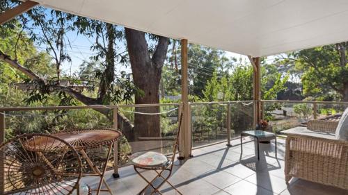 a screened porch with chairs and a tree at Binda Beauty in Hawks Nest