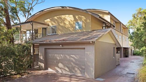 a house with a garage and a building with an arch at Binda Beauty in Hawks Nest