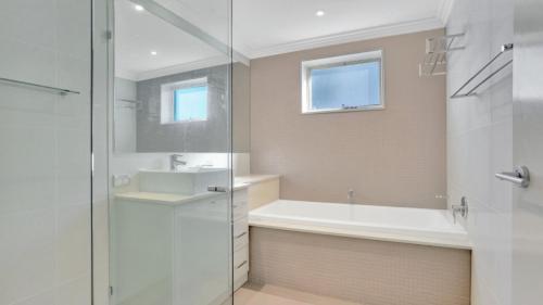 a bathroom with a shower and a tub and a sink at 1 - 58 Moira Pde, Hawks Nest in Hawks Nest