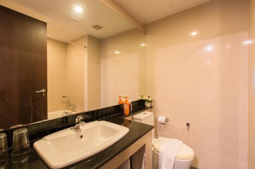 a bathroom with a sink and a toilet and a mirror at Kris - Modern Spacious 2 Bedroom Condo with Pool in Patong Beach