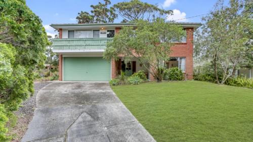 a house with a green garage in the yard at 4 Kururma Crescent Hawks Nest in Hawks Nest