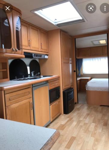 a kitchen with wooden cabinets and a bed in an rv at Nannys tiny hoose in Inverness