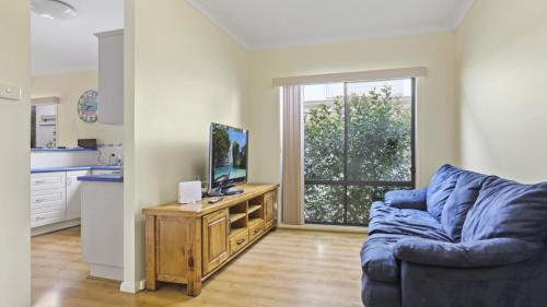 Sunset Cottage في هاوكس نيست: غرفة معيشة بها أريكة زرقاء وتلفزيون