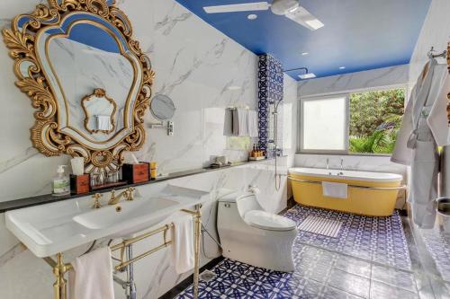 uma casa de banho com um lavatório, uma banheira e um espelho. em Mayfair On Sea, Morjim Beach, Goa em Morjim
