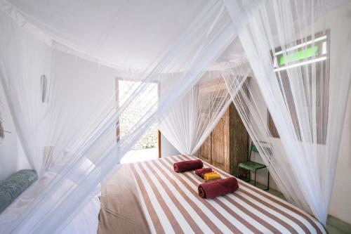 1 dormitorio con cama blanca con dosel y almohadas rojas en Villa Papaya & Zen, en Uluwatu