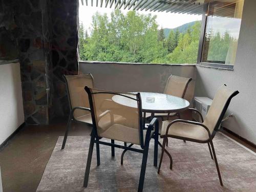 einen Tisch und Stühle in einem Zimmer mit Fenster in der Unterkunft Hotel Alpin Aparthotel Apartament 301 in Poiana Brașov