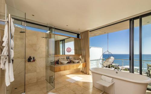 ein Bad mit einer Badewanne und einer Dusche mit Aussicht in der Unterkunft CapeStays - Villa Infinity in Kapstadt