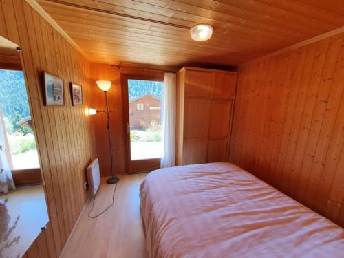 a small bedroom with a bed in a wooden room at Chalet individuel 8 pers à Chatel Porte du soleil avec Jacuzzi exterieur in Châtel