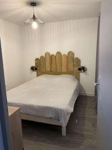 um quarto com uma cama e uma cabeceira em madeira em T2 Arcachon (Aiguillon) accès immédiat à la plage em Arcachon
