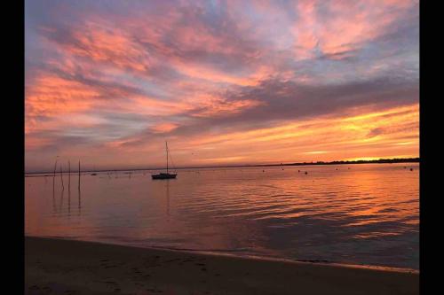 阿爾卡雄的住宿－T2 Arcachon (Aiguillon) accès immédiat à la plage，海滩上的日落,在水中乘船