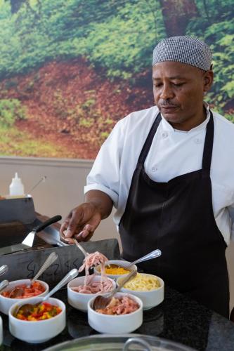 Gooderson Monks Cowl Golf Resort في Champagne Valley: رجل في مطبخ يُعد الطعام في أوعية