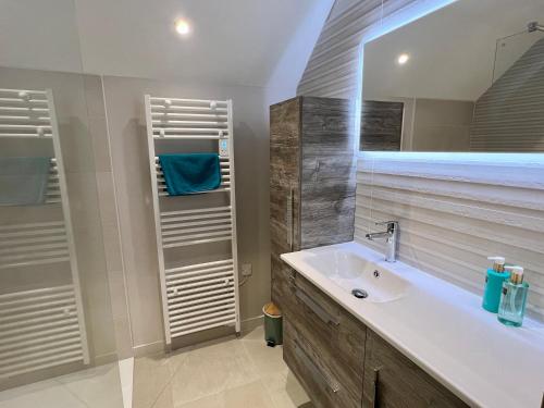 een badkamer met een wastafel en een spiegel bij Maison « Embruns de mer » à 800 m de la mer in La Pironnière