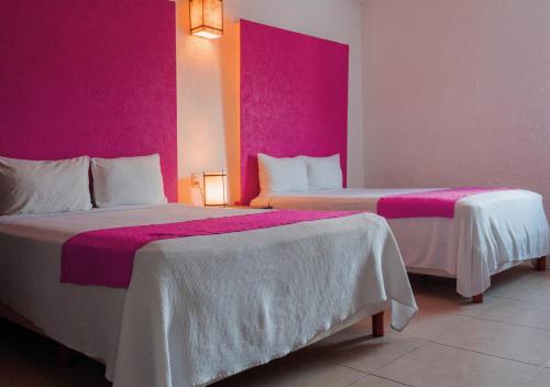 two beds in a hotel room with pink walls at Nina Hotel Playa del Carmen in Playa del Carmen